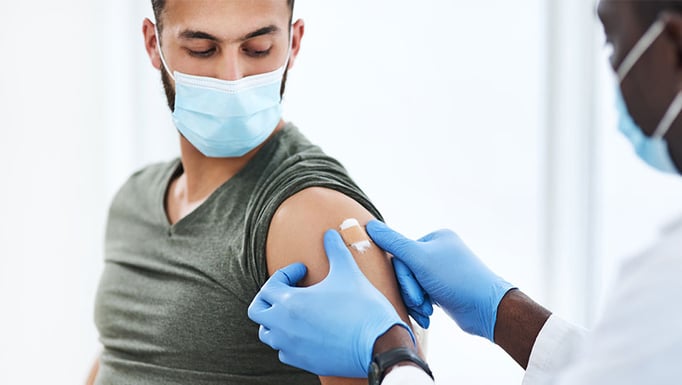 Masked provider places bandaid on masked patient
