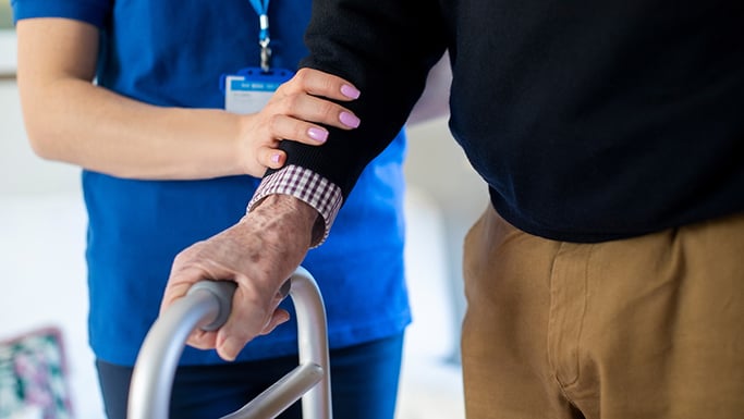 Nurse helping senior man with walker