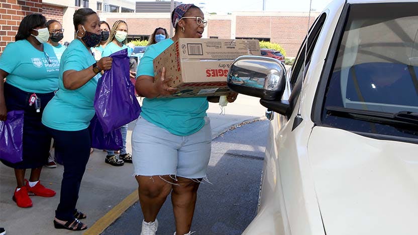 Sharice Williams hands a box of diapers to a local family participating in the Drive-Thru Baby Shower, hosted Sept. 17 at UChicago Medicine Ingalls Memorial Hospital. As community outreach coordinator at Ingalls, Williams helped launch the event in 2020.