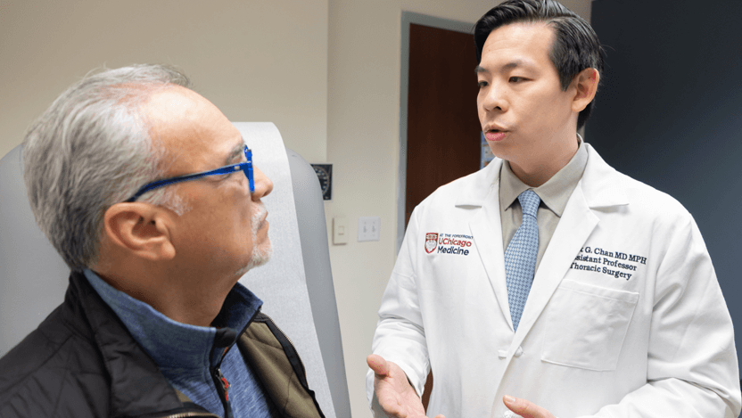 Thoracic surgeon Ernest Chan, MD, MPH, meets with a patient in clinic