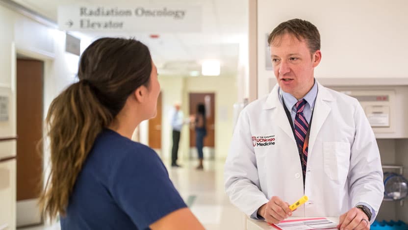 Radiation oncologist Steven Chmura, MD, meets with a staff member in clinic