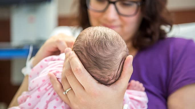 Mom cradles newborn in bed