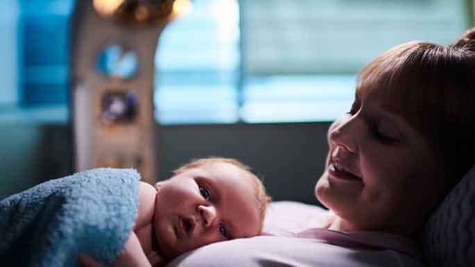 Mom in hospital bed with sleeping baby on chest