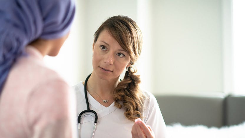 A medical professional discusses options with a patient who is wearing a head scarf.
