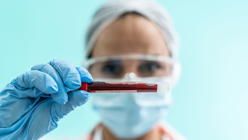 Person wearing PPE holding blood sample