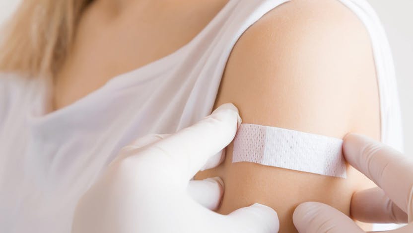 A doctor puts a bandage on a women's arm after getting a HPV vaccine