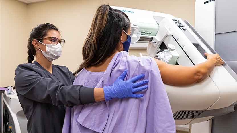 View of patient from rear as technician performs mammogram