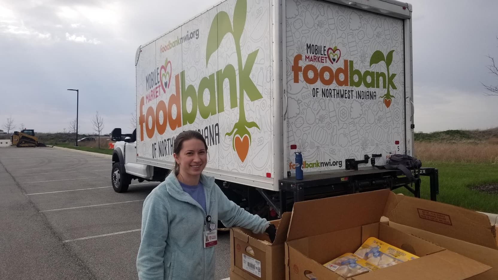 A volunteer poses with a food bank truck