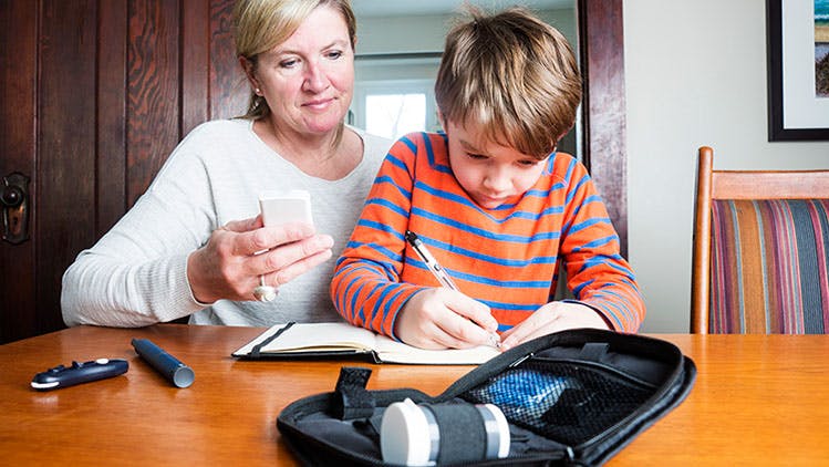 Mom helping her son monitor diabetes