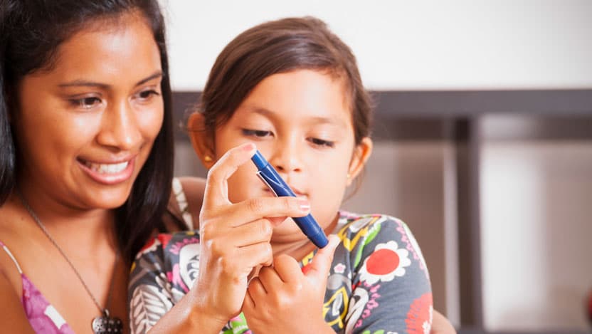 A photograph of a mother helping her diabetic child monitor her blood sugar.