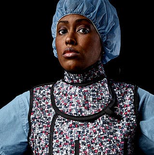 Chelsea Dorsey, MD, wearing surgical scrubs staring into the camera against a black background.