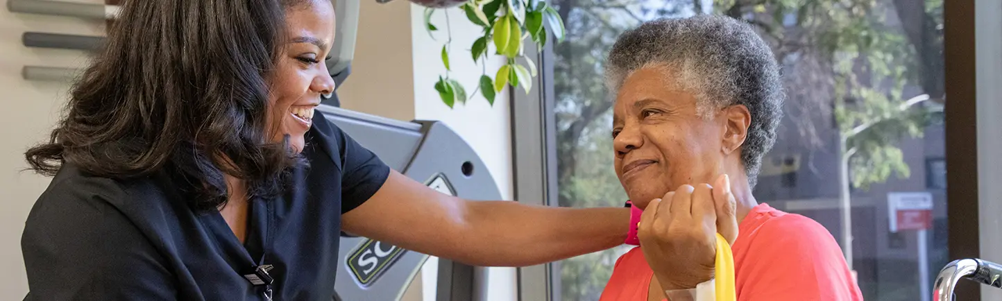 A female patient in a wheel chair receiving physical therapy from a female therapist.