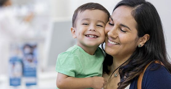 Image of pediatric hematology patient smiling with mother