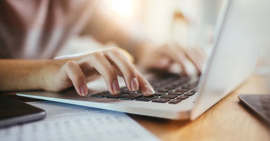 women's hands typing on laptop keyboard