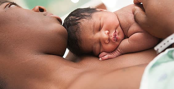 Close-up of mom resting and cradling newborn skin-to-skin on her chest