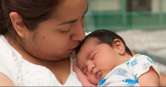 mom kissing newborn baby on head