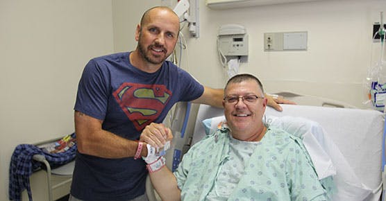Kidney transplant patient Stewart Botsford (in bed) and his donor, Justin Maduena, visit with each other in Mitchell Hospital after their surgeries two days earlier on August 18, 2016, at University of Chicago Medicine