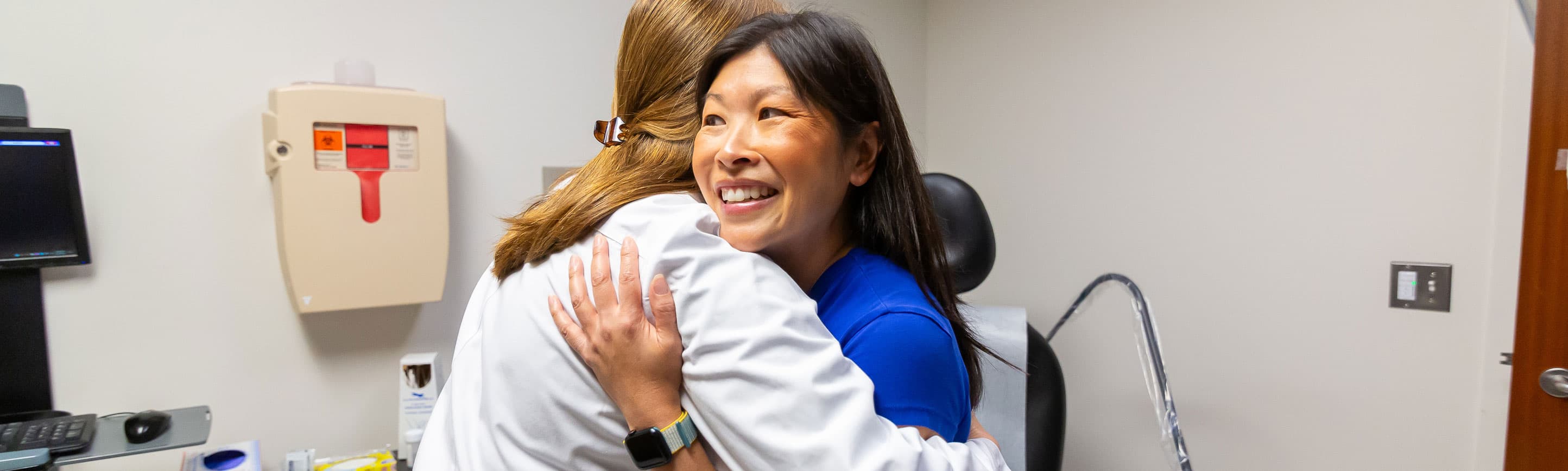 gynecologic oncologist Kathryn Mills, MD, hugs a patient in clinic