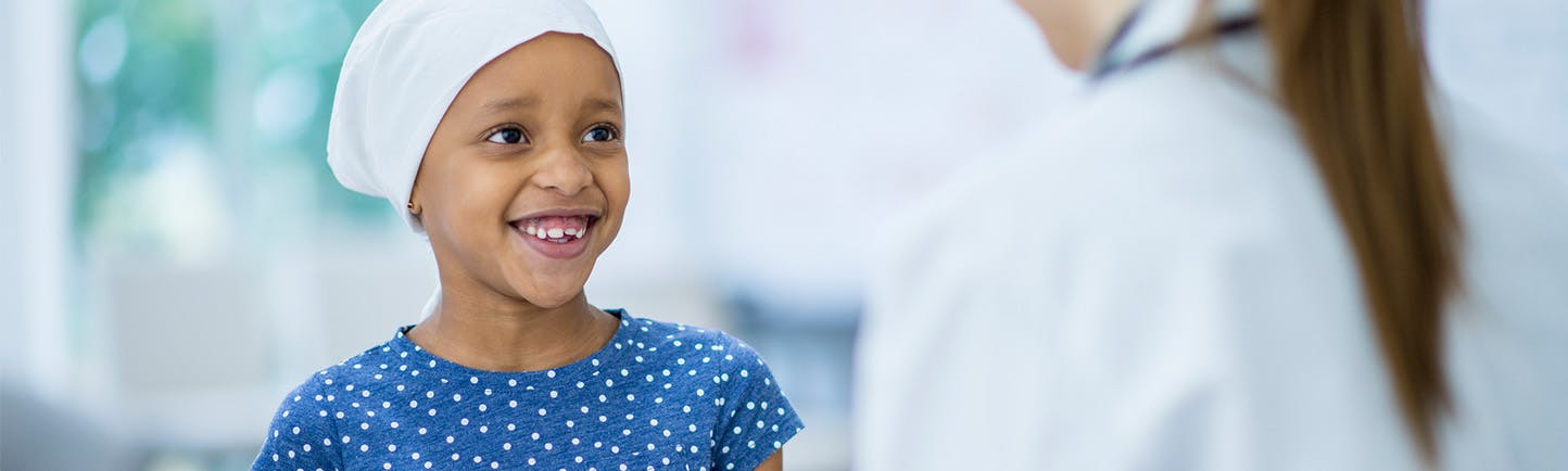 Image of childhood leukemia patient smiling and talking to provider